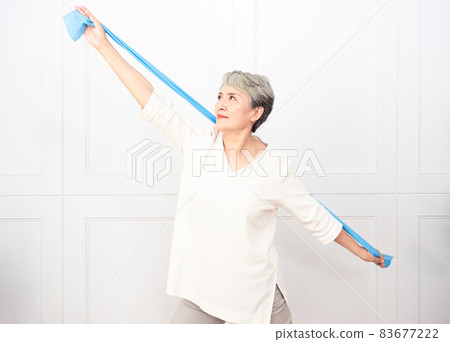 Senior asian woman doing exercises with resistance band at home. Senior asian woman doing exercises with resistance band at home. 83677222