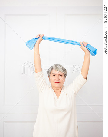 Senior asian woman doing exercises with resistance band at home. Senior asian woman doing exercises with resistance band at home. 83677224