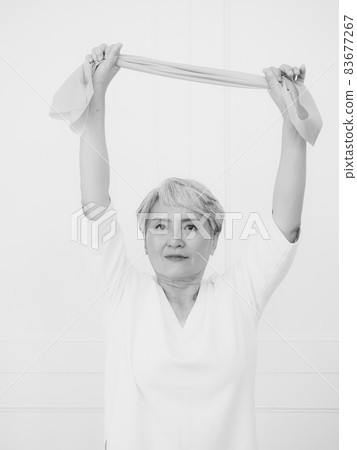 Senior asian woman doing exercises with resistance band at home. Senior asian woman doing exercises with resistance band at home. 83677267