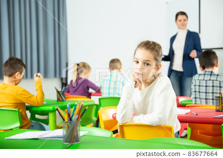 Portrait of tired schoolgirl sitting in classroom elementary school Portrait of tired schoolgirl sitting in classroom elementary school 83677664