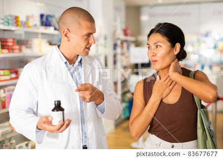 Pharmacist offering medicine for sore throat to patient at pharmacy closeup Pharmacist offering medicine for sore throat to patient at pharmacy closeup 83677677