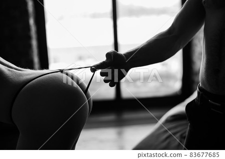 Close-up Of Woman's Hand Pulling Man's Underwear On White