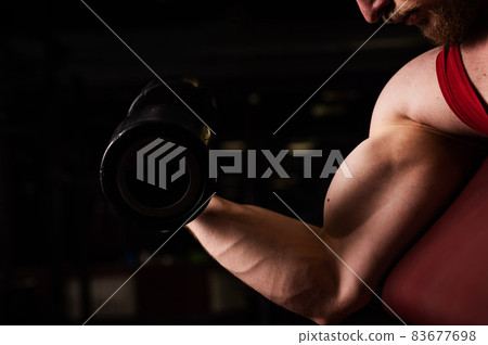 Unrecognizable man doing biceps exercise in the gym. Muscular man is engaged in bodybuilding. Close-up of male hands. Unrecognizable man doing biceps exercise in the gym. Muscular man is engaged in bodybuilding. Close-up of male hands. 83677698