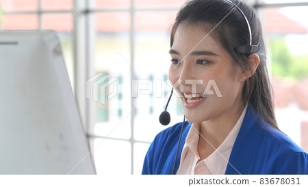 Businesswoman wearing headset working actively in office Businesswoman wearing headset working actively in office 83678031