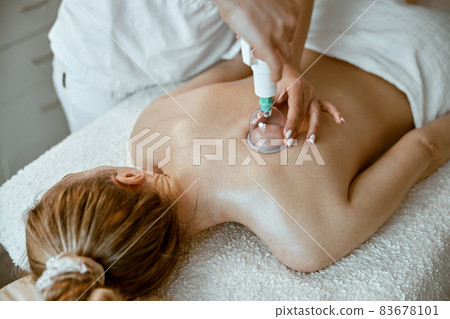 professional female specialist is doing cupping therapy on the back of beautiful caucasian lady professional female specialist is doing cupping therapy on the back of beautiful caucasian lady 83678101
