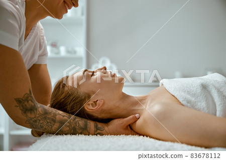 Adult female specialist is doing neck massage to a young natural beautyful female client 83678112