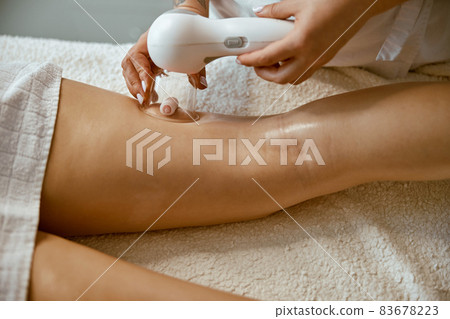 Confident female specialist is doing anticellulite leg massage to beautiful healthy caucasian female client 83678223