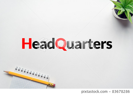 Business acronym HQ or Headquarters. On the table a flower and a notebook with a pencil Business acronym HQ or Headquarters. On the table a flower and a notebook with a pencil 83678286