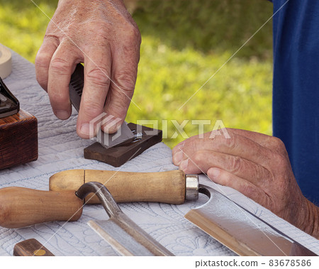 Man Sharpens Plane Blade on Oiled Whetstone 83678586