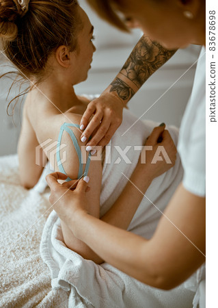 Confident female doctor is doing taping procedure in modenr treatment cabinet Confident female doctor is doing taping procedure in modenr treatment cabinet 83678698