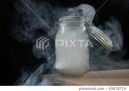 Glass jar with a lid filled with smoke on a black background. Fog in a transparent container on the table. Glass jar with a lid filled with smoke on a black background. Fog in a transparent container on the table. 83678729