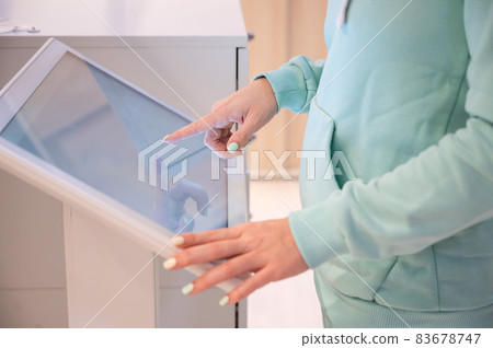 Faceless woman touching the screen of a self-service device in a store. Device store navigator. Self purchase. 83678747