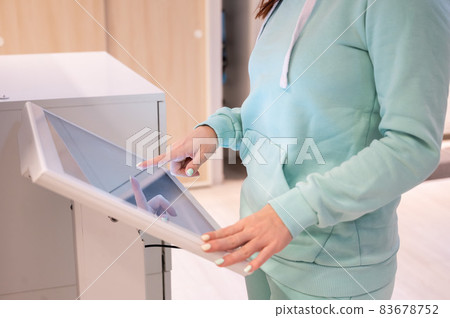 Faceless woman touching the screen of a self-service device in a store. Device store navigator. Self purchase. 83678752