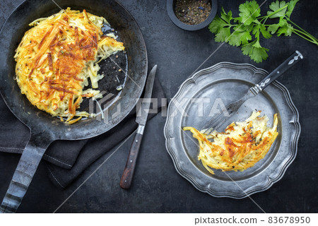 Traditional Swiss rosti as side dish offered as top view in frying pan 83678950