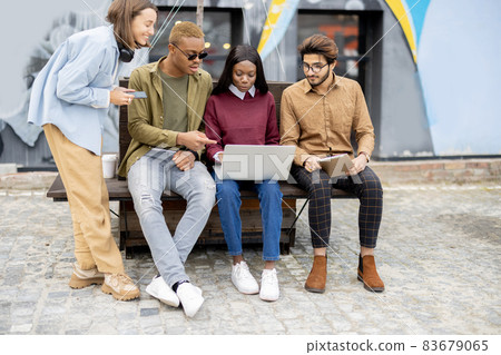 Multiracial students watch some on laptop outdoors Multiracial students watch some on laptop outdoors 83679065