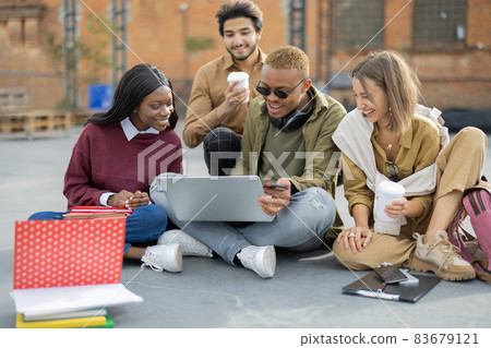 Students watching something on laptop on asphalt Students watching something on laptop on asphalt 83679121
