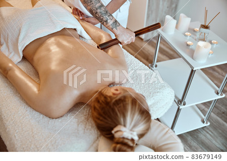 Professional confident massage master is doing procedures to caucasian woman in minimalistic modern cabinet Professional confident massage master is doing procedures to caucasian woman in minimalistic modern cabinet 83679149