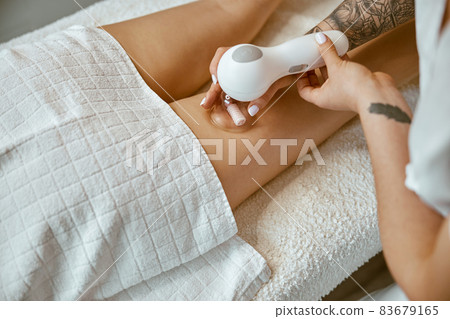 Confident female specialist is doing anticellulite leg massage to beautiful healthy caucasian female client 83679165