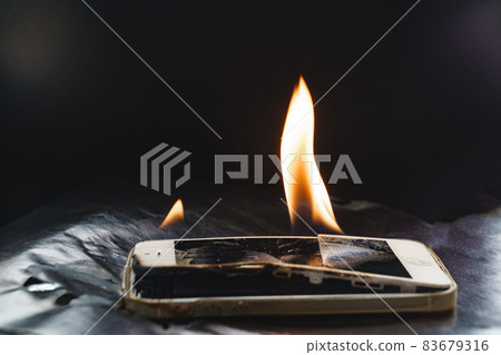 burning broken smartphone on a black background.  83679316