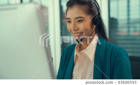 Businesswoman wearing headset working actively in office Businesswoman wearing headset working actively in office 83680593