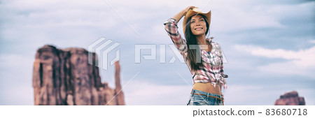 Cowgirl western cowboy hat Asian woman walking in Monument Valley. Beautiful young girl in summer outdoors, Arizona Utah, USA. Banner panorama. 83680718