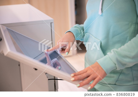 Faceless woman touching the screen of a self-service device in a store. Device store navigator. Self purchase. 83680819