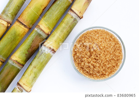 Sugar cane with brown sugar on white background Sugar cane with brown sugar on white background 83680965