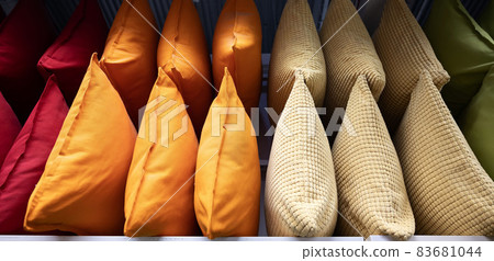 A row of colorful pillows on a shelf in a textile store. A row of colorful pillows on a shelf in a textile store. 83681044