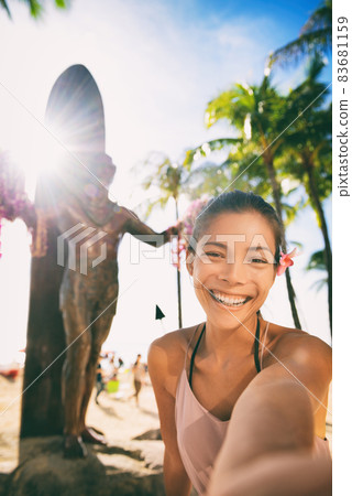 Hawaii summer vacation woman taking selfie photo on Waikiki Beach at Duke Kahanamoku statue, famous tourist attraction in Honolulu, Oahu Hawaii. Hawaii summer vacation woman taking selfie photo on Waikiki Beach at Duke Kahanamoku statue, famous tourist attraction in Honolulu, Oahu Hawaii. 83681159