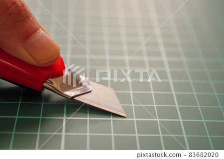 Close up by pressing the blade of the cutter against the green cutting board and folding it Close up by pressing the blade of the cutter against the green cutting board and folding it 83682020