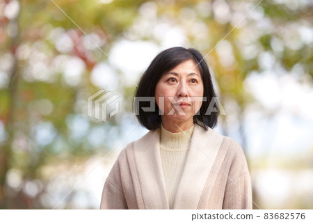 A lonely middle-aged woman in an autumn park 83682576