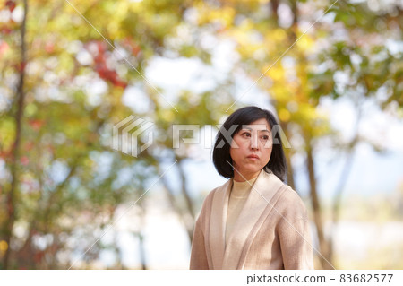 A lonely middle-aged woman in an autumn park 83682577