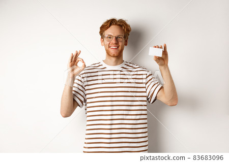 Shopping and finance concept. Satisfied male bank client showing OK sign and plastic credit card, smiling happy at camera Shopping and finance concept. Satisfied male bank client showing OK sign and plastic credit card, smiling happy at camera 83683096