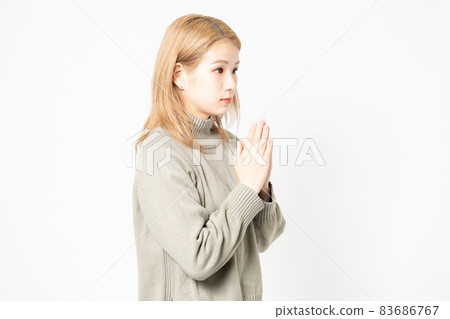 一個穿毛衣的年輕女人要她把手掌放在一起 一個穿毛衣的年輕女人要她把手掌放在一起 83686767