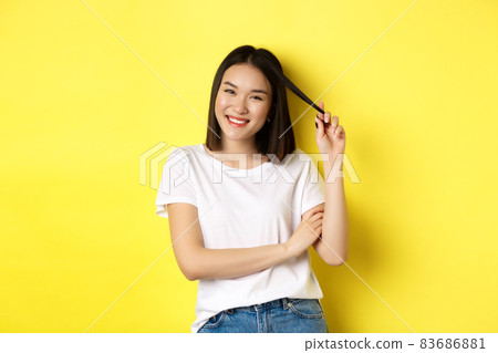 Confident and stylish asian woman cross arms on chest and smiling, standing over yellow background 83686881