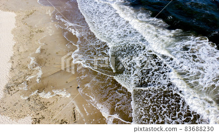 Aerial drone view flight over sea waves that roll onto sandy shore. Aerial drone view flight over sea waves that roll onto sandy shore. 83688230