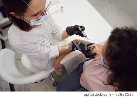 Top view of a woman in medical protective mask being vaccinated with corona virus vaccine.Voluntary vaccination concept to fight the spread of infectious viral disease. Immunization of the population 83688535