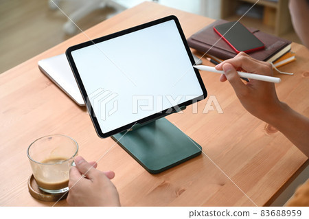 Young man holding coffee cup and using digital tablet in living room. 83688959