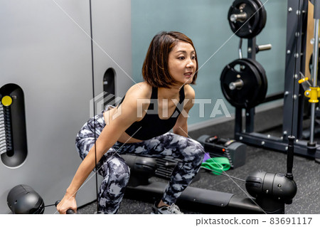 A woman doing muscle training in a sports gym A woman doing muscle training in a sports gym 83691117