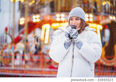 Half length of Young beautiful girl who walks on holiday city while drinks hot coffee. Festive mood Half length of Young beautiful girl who walks on holiday city while drinks hot coffee. Festive mood 83693023