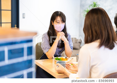 Two young women wearing masks and having lunch 83696993