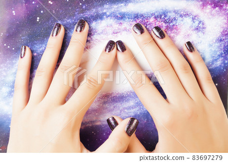 manicure stylish concept: woman fingers with nails purple glitter on nails like cosmos, universe background manicure stylish concept: woman fingers with nails purple glitter on nails like cosmos, universe background 83697279