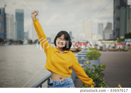 asian teenager happiness raising hand against city skyline 83697617