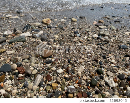 Sea gravel shore or beach with sea water at sunset 83698043