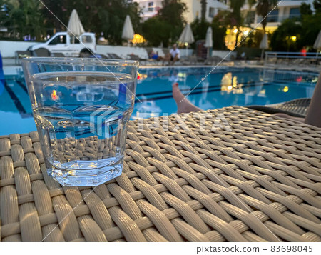 Glasses with tasty cocktail in front of a swimming pool with clear water. Close-up photo. Palm trees on the background. Vacation 83698045