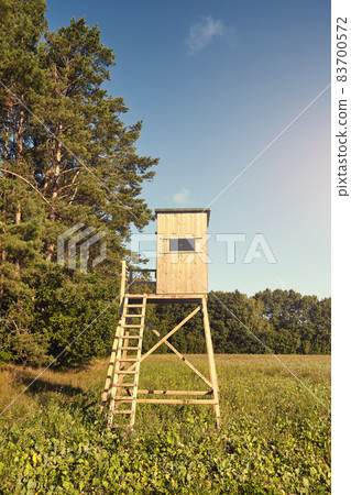 Wooden deer and wild boar hunting blind stand on a field at sunset. Wooden deer and wild boar hunting blind stand on a field at sunset. 83700572
