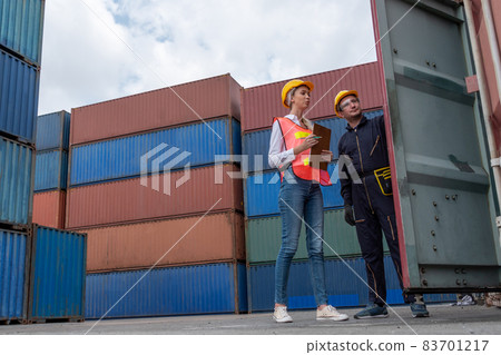 Industrial worker works with co-worker at overseas shipping container yard 83701217