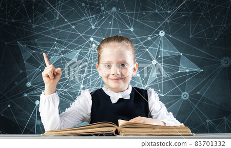 Smiling little girl sitting at desk with open book Smiling little girl sitting at desk with open book 83701332