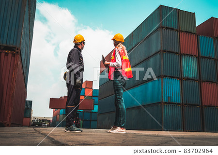 Industrial worker works with co-worker at overseas shipping container yard 83702964