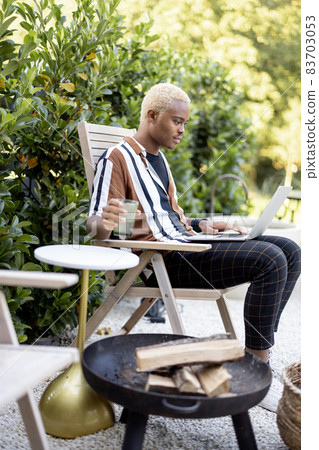 Latin man using laptop on lounger at house garden 83703053